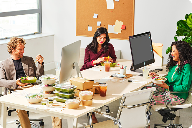 people sitting around a table with computers enjoying lunch