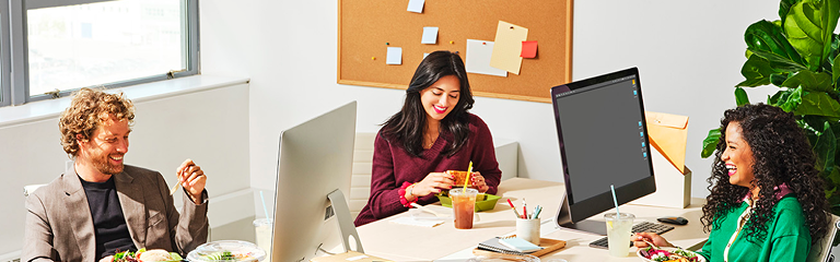 people sitting around a table with computers enjoying lunch